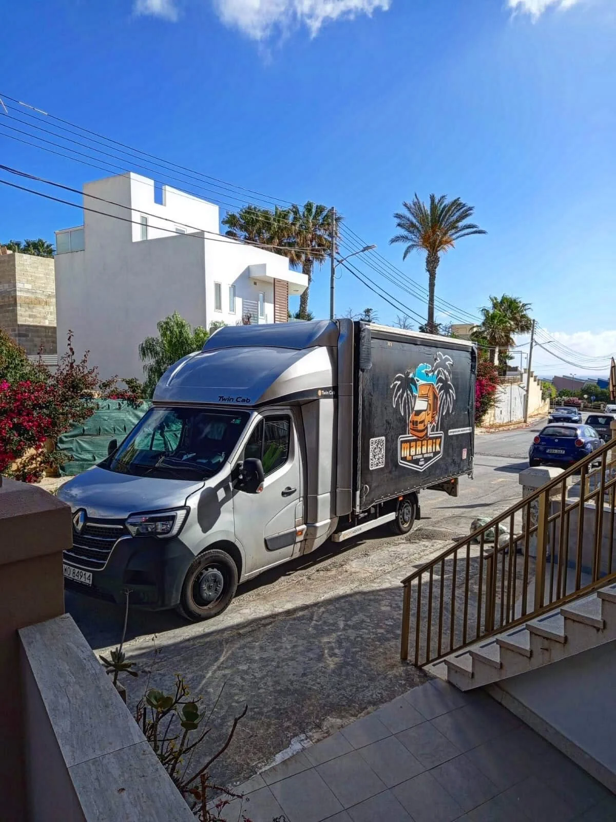 Grey Mararik Express Renault on a sunny street with palm trees